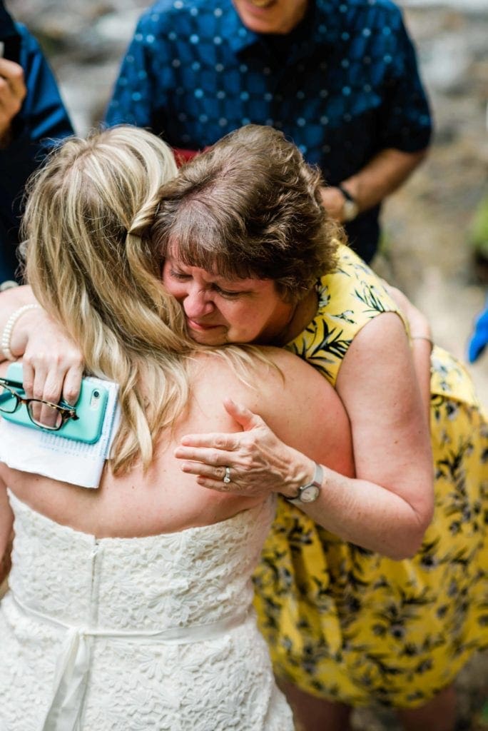 After vow reading in an adventure elopement with family, a mother tearfully hugs the bride