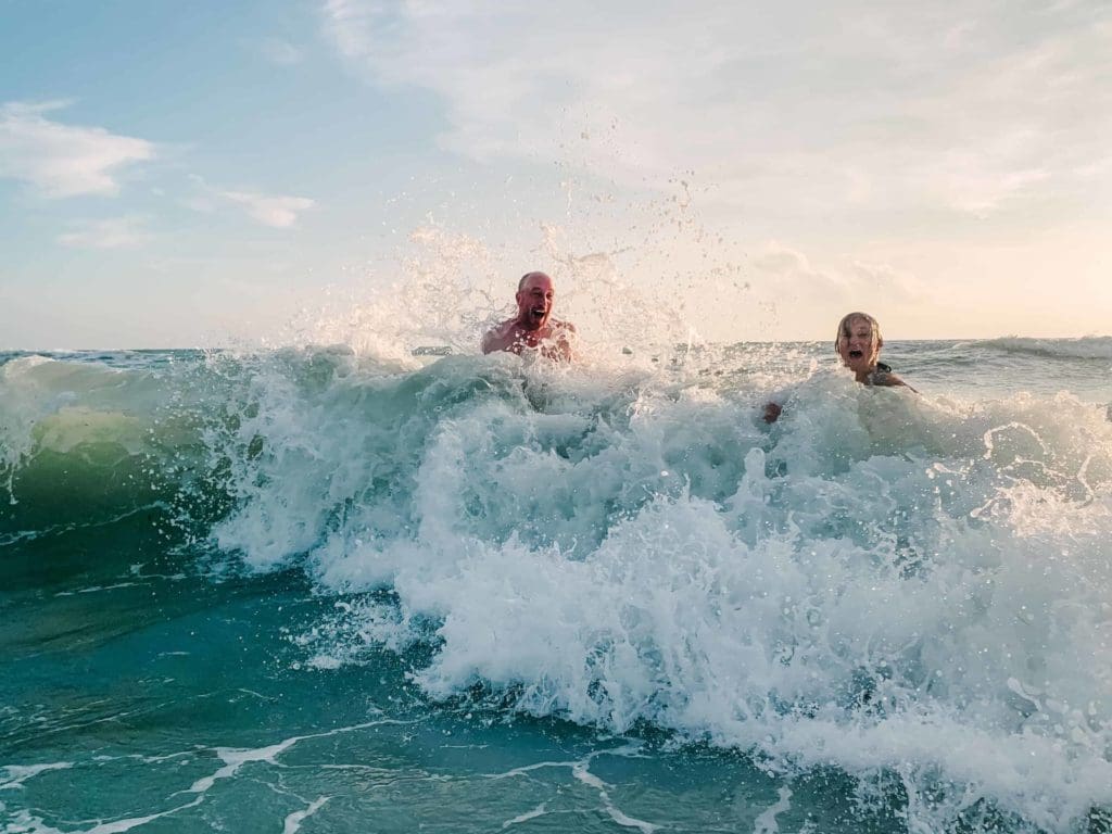 In this image you see a man and woman laughing together in the ocean. This picture was taken during their adventure elopement in Georgia. After their vows, they decided to job in the water to celebrate!