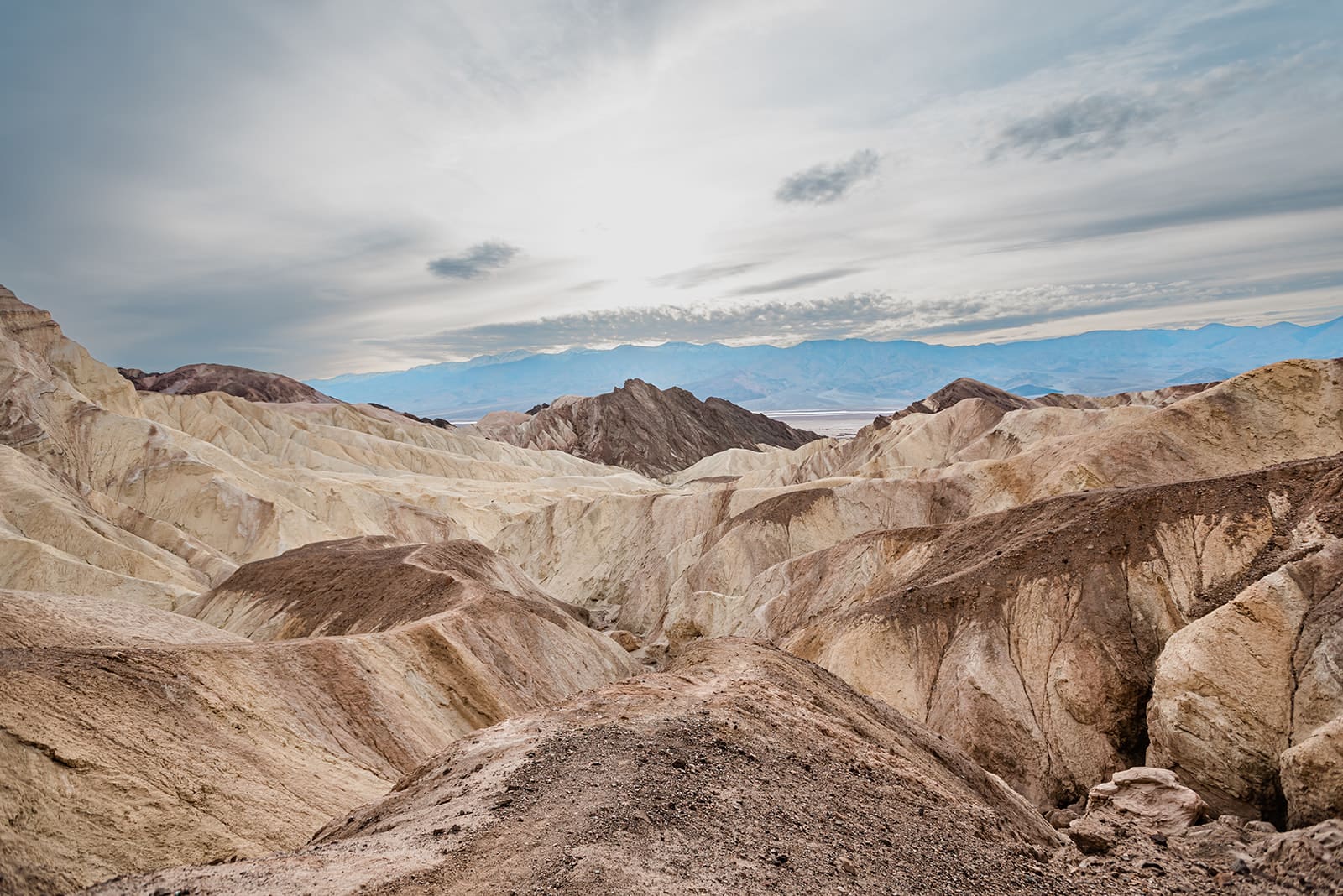 This is a picture taken of a California national park. It is a rocky landscape with a bright blue sky. There are peaks and valleys filling the entire landscape.