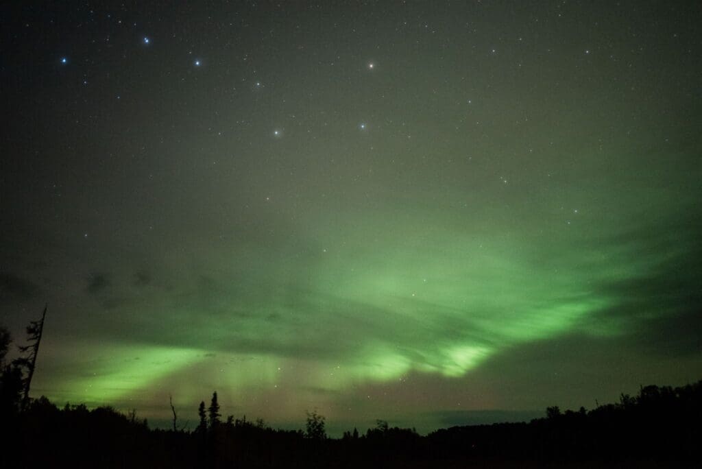 an elopement package in Alaska to chase the aurora borealis for your wedding where the green lights of the aurora borealis dance in the night sky with the Big Dipper shining bright