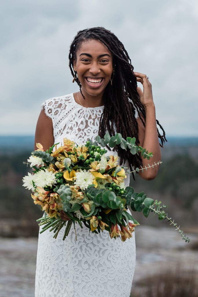 This is a bride smiling at the camera. She's holding her bright yellow flowers.