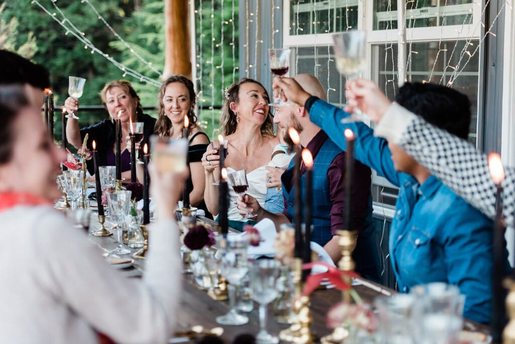 This is a picture of a bride and groom celebrating with their loved ones. They are sitting at a table together and raising glasses to celebrate.