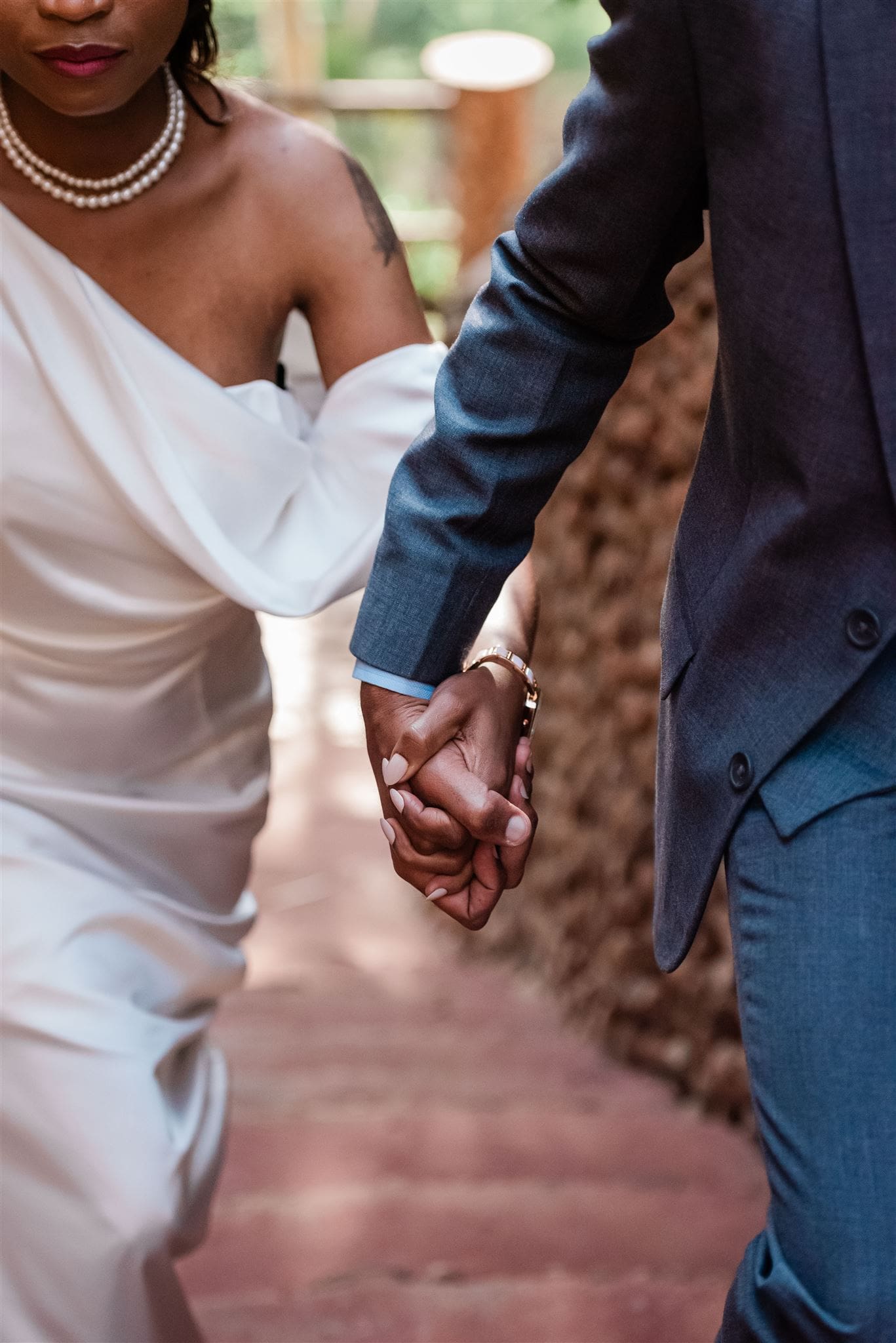 This is a picture of a bride and groom walking together and holding hands.