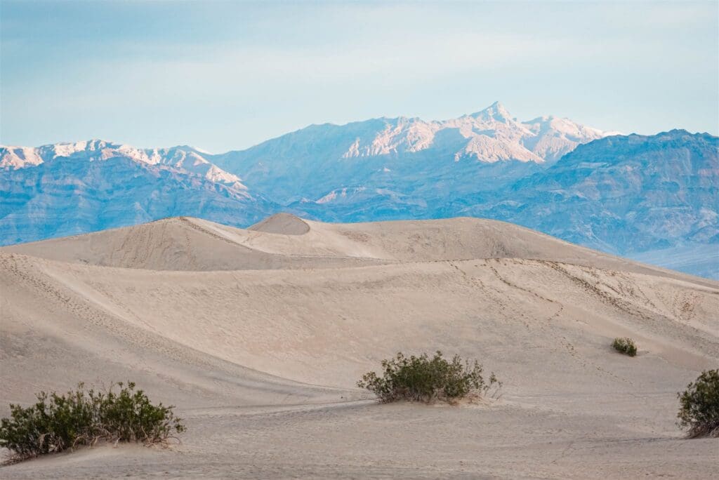 Sweeping sand dunes with snow capped mountains in the background as epic off-the-beaten-path international elopement destinations