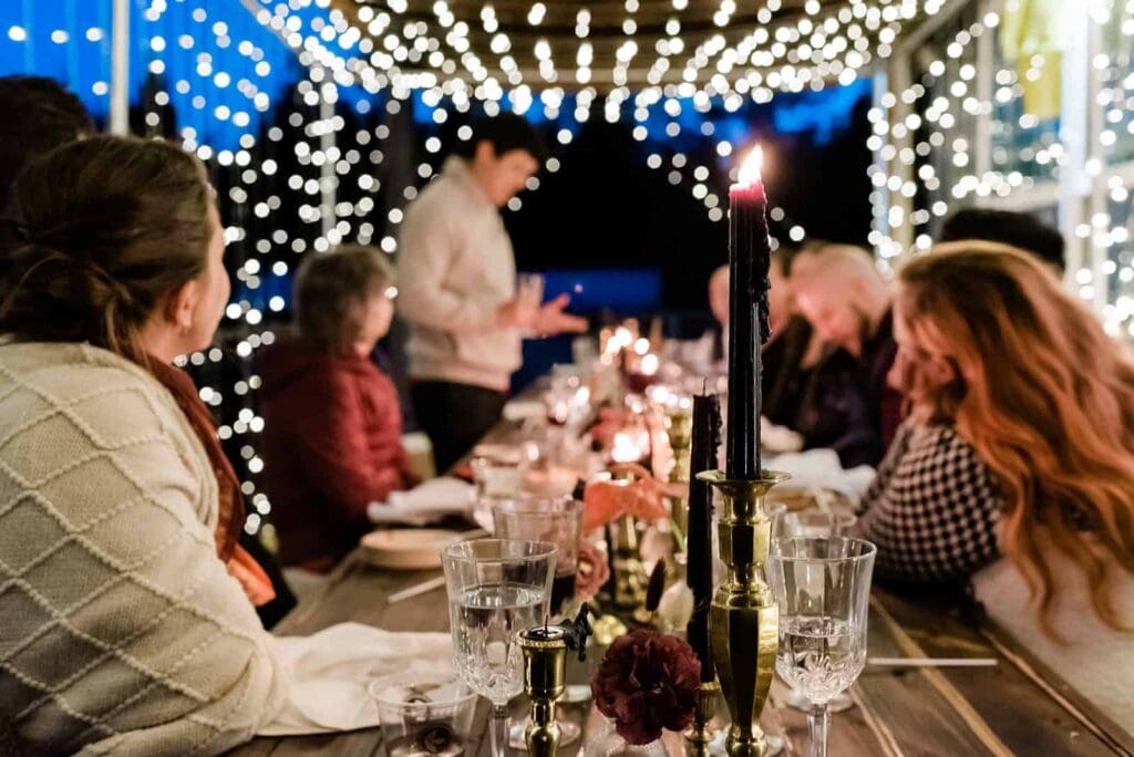 An Alyeska Airbnb rental for an intimate wedding is a cozy way to elope in Alaska.  The long dinner table is beautifully styled and a guest gives a speech under the canopy of twinkle lights. 