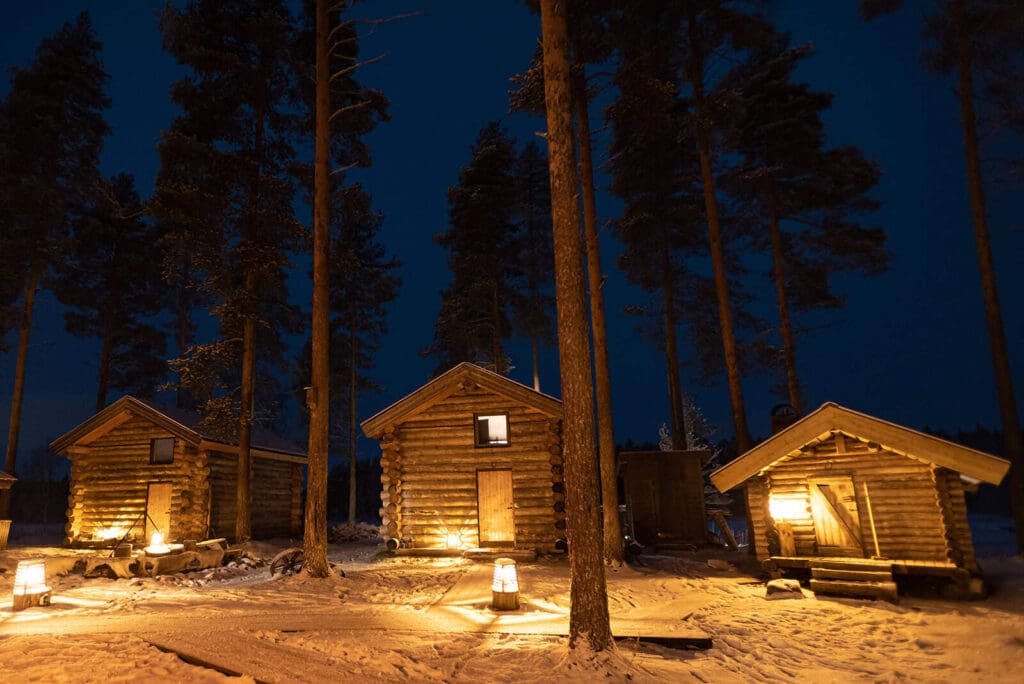 Cozy winter scenes of snowy cabins at night to inspire ways to elope in Alaska in Winter.