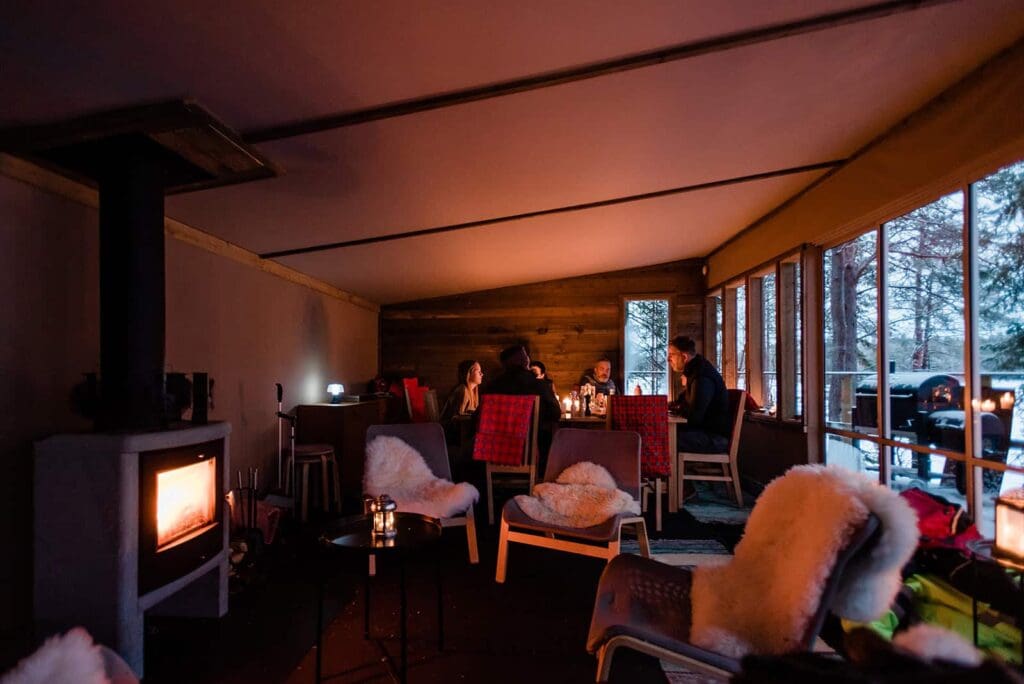 A cozy family Alaska elopement winter scene in the glow of candles inside a fire warmed luxury glamping community area. 