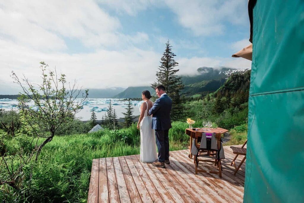 at the Bear Glacier Lagoon, a couple gets ready for day two of their adventure luxe glamping elopement in Seward, overlooking the iceberg-filled lagoon the took a helicopter to reach. 