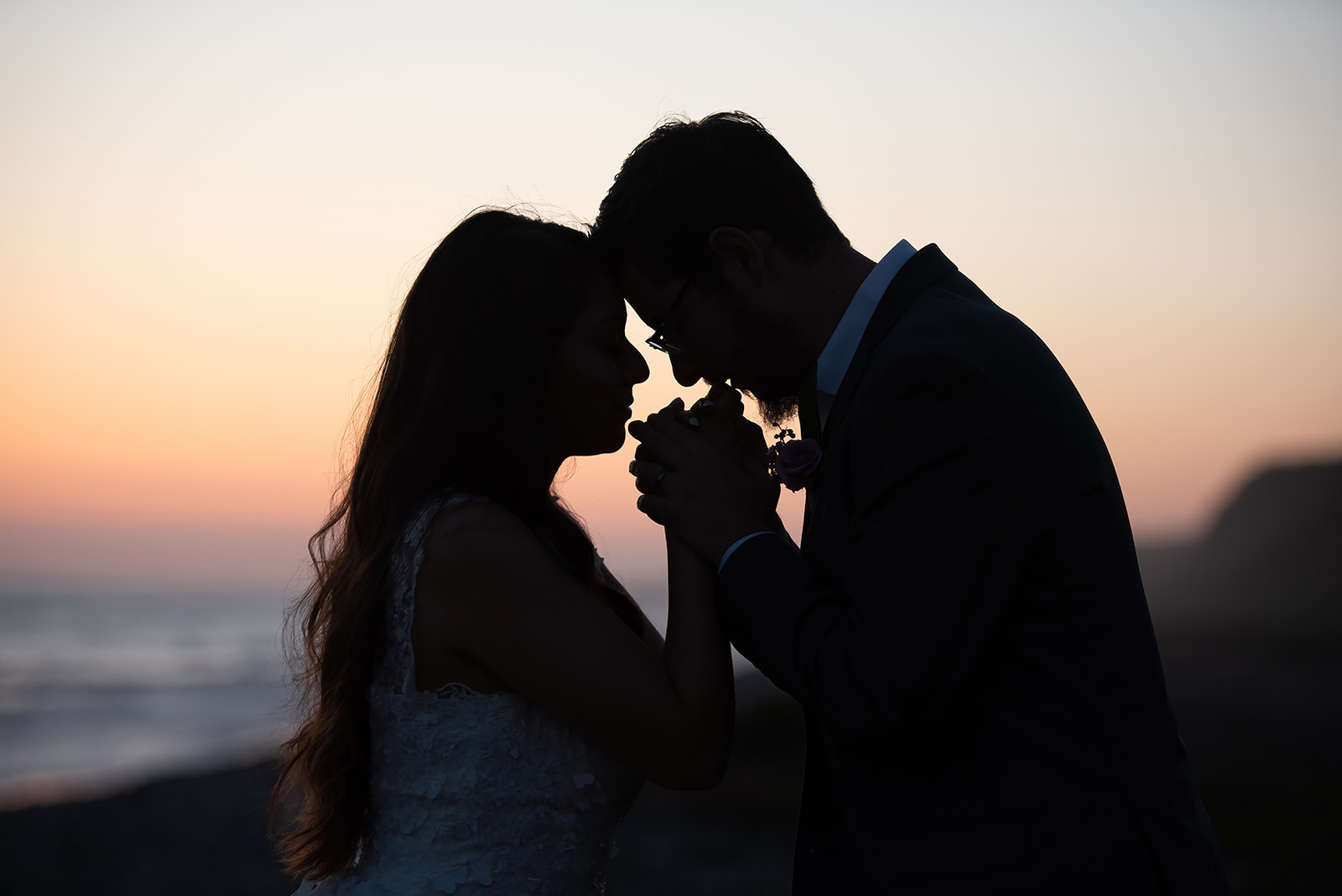 At their luxury beach-side elopement, this could shares an intimate moment at sunset.