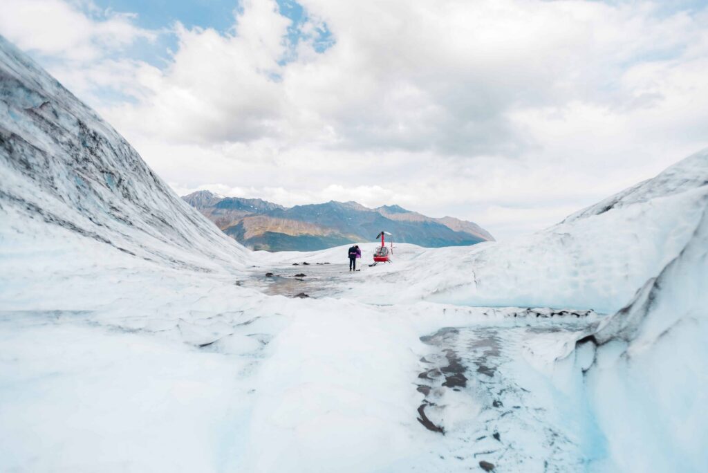 Surrounded by the deep dimensions of Herbert Glacier, this couple in their warm wedding best are hugging as they take in the grand views of their secluded helicopter stop.